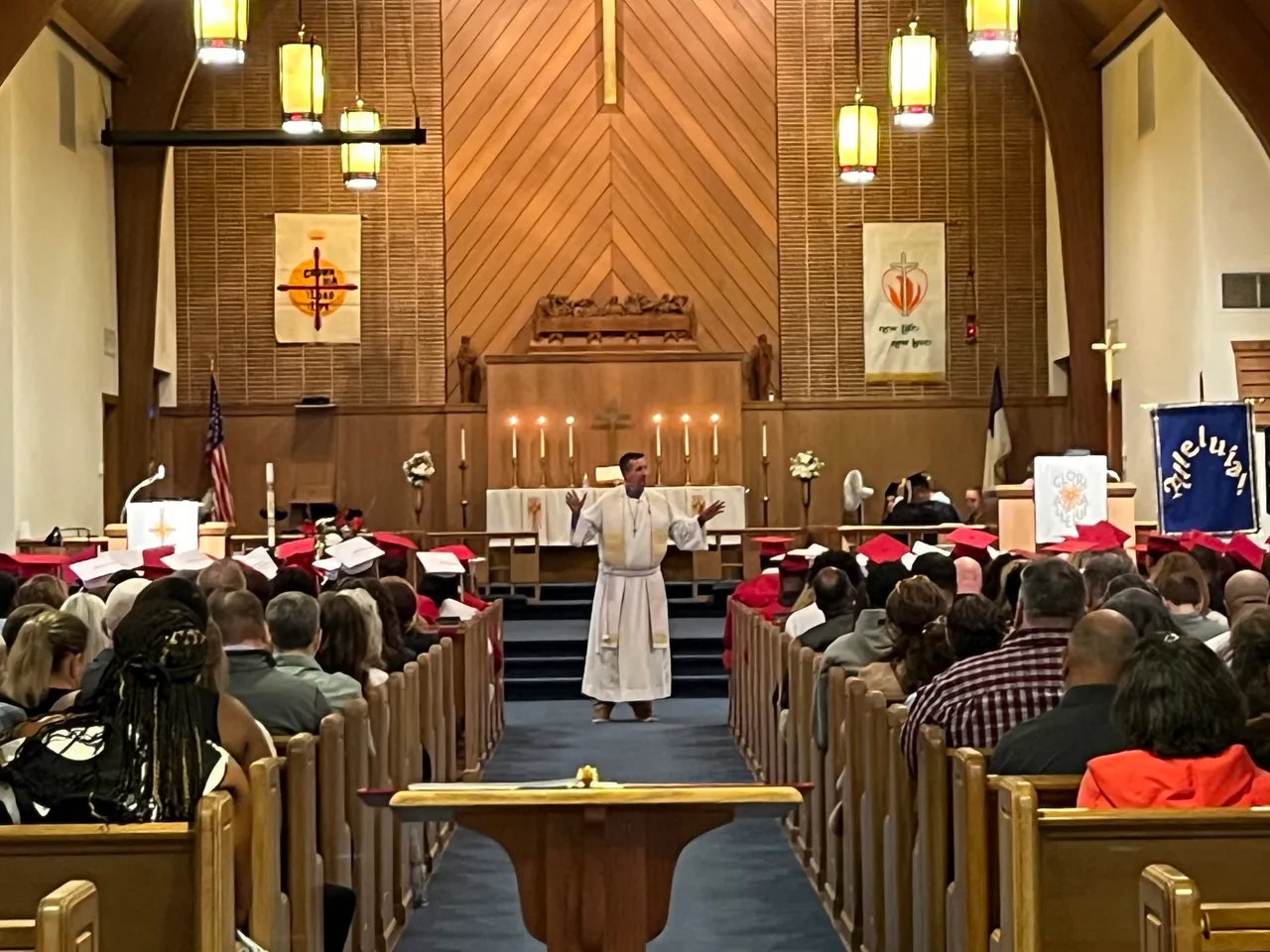 Image of pastor speaking in front of congregation of families, students, and parishioners.