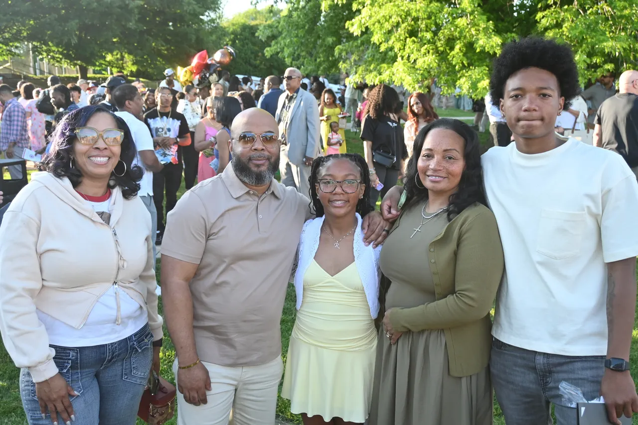 Members of the Saints family posing with student on the back quad after an event.