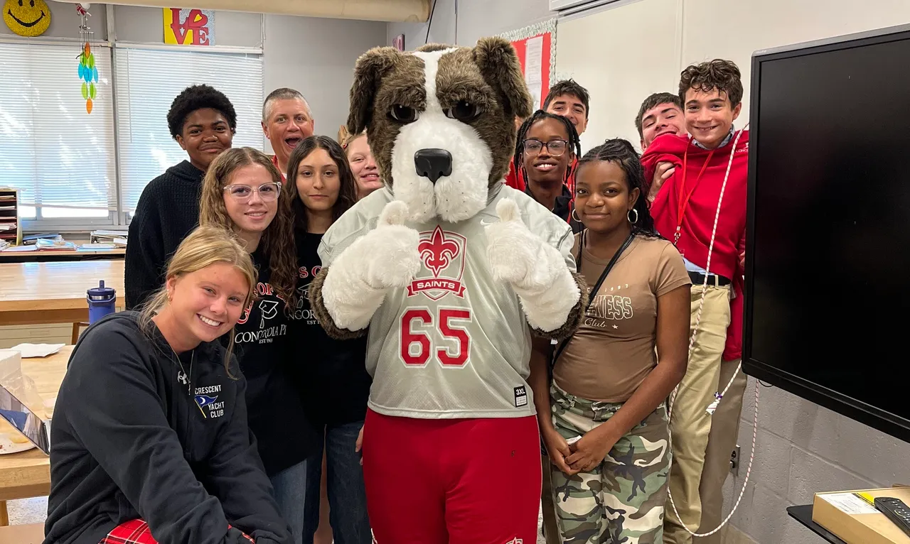 Students and faculty posing with mascot in classroom.