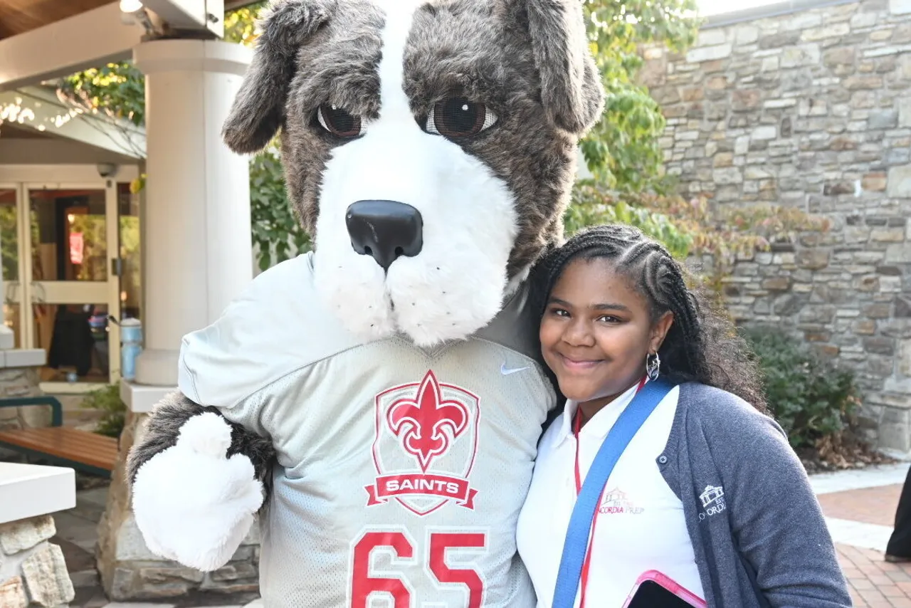 Luther the SAINT Bernard mascot and student pose for photo