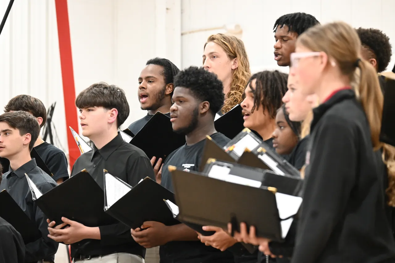 Members of the Concert Choir singing at concert in Saints Gym.