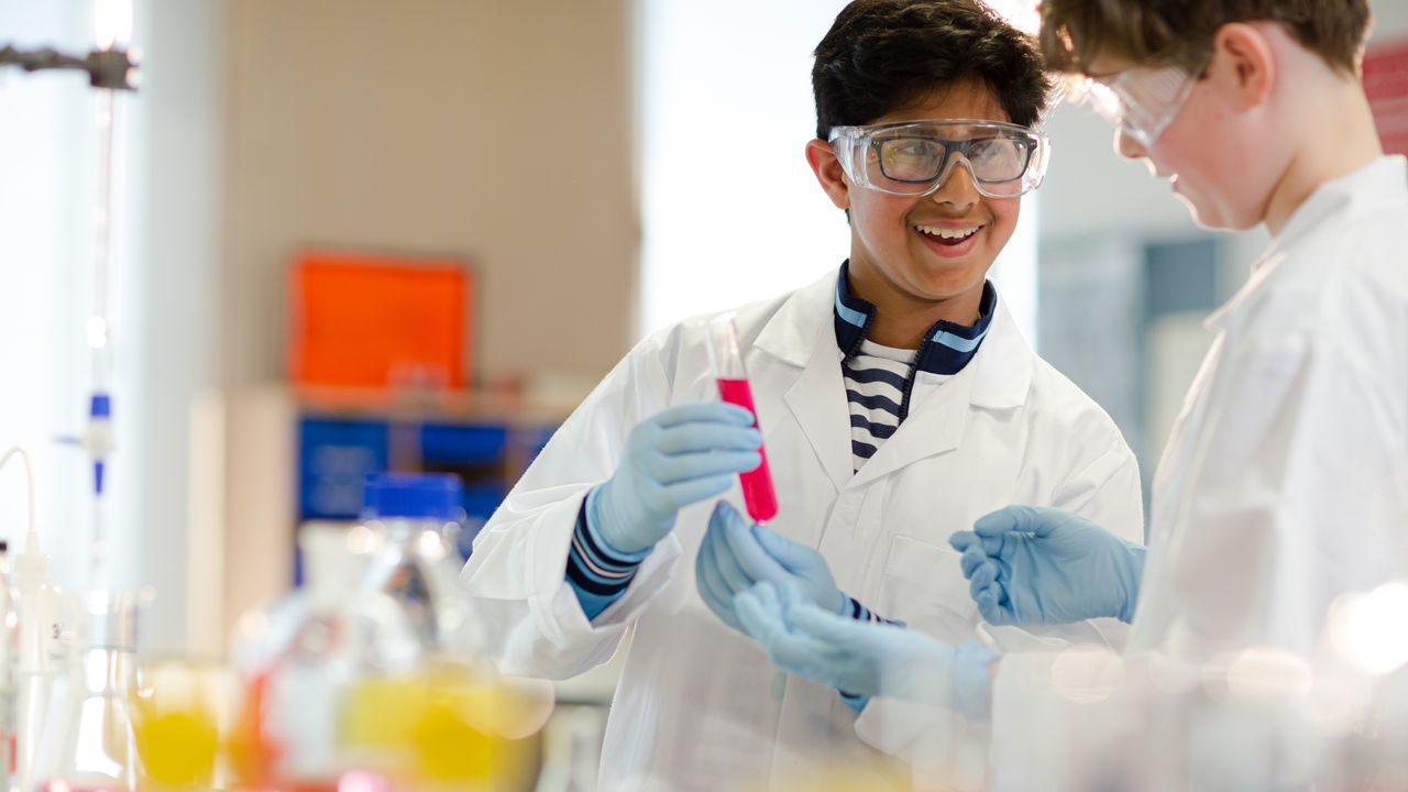 Middle School Student in lab coat holding test tub