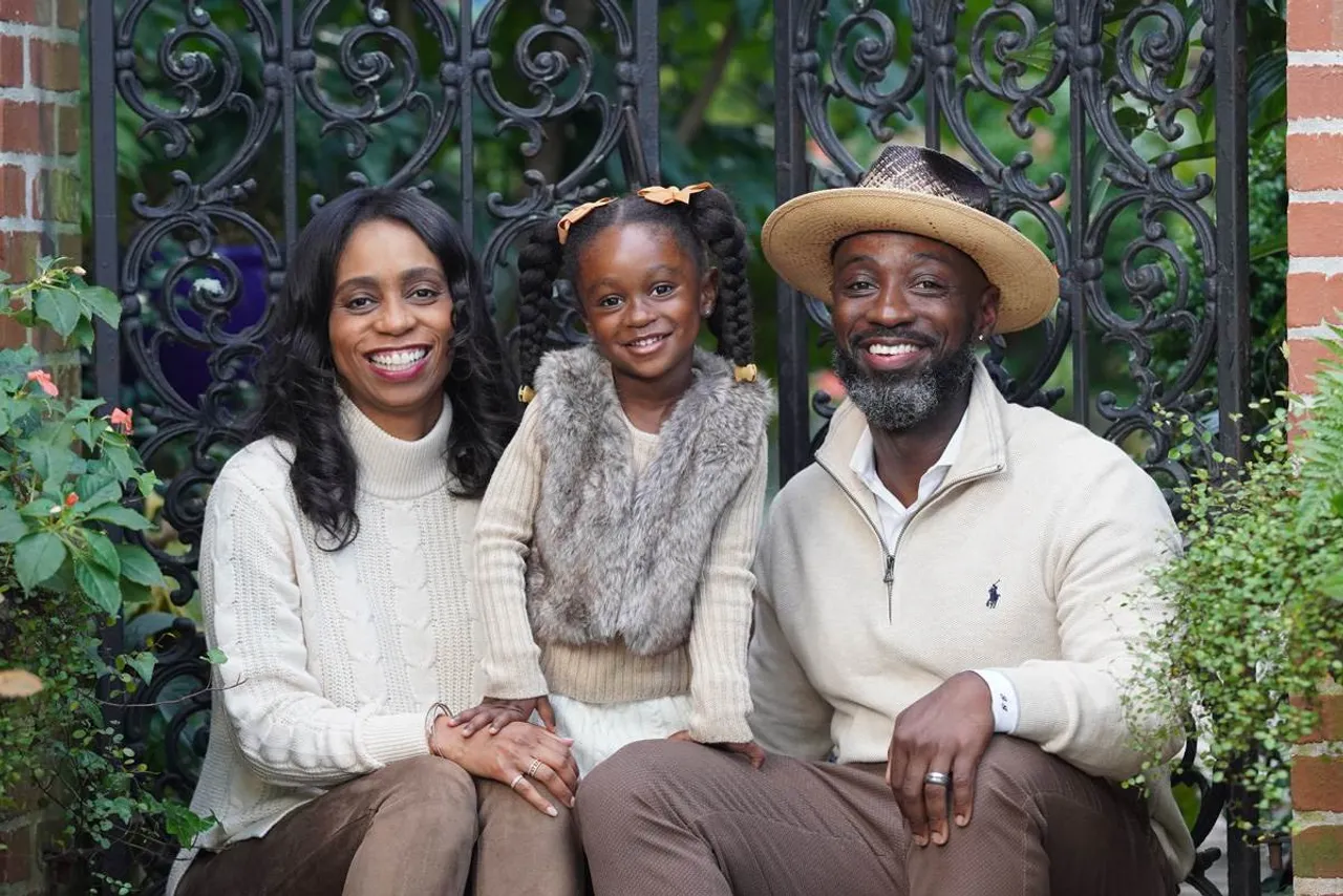 Current parents pictured with their daughter outdoors.