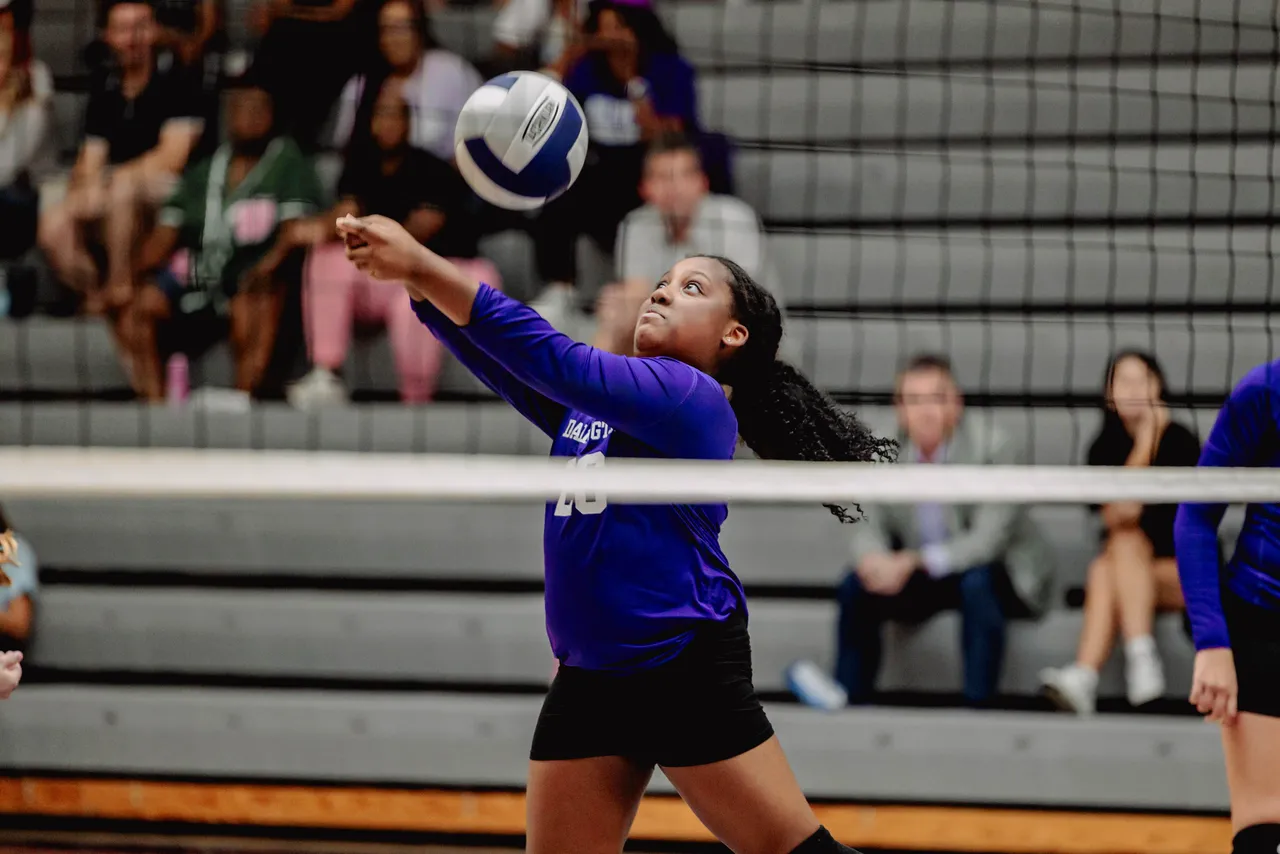 Female middle school JV volleyball player passes the ball during a volleyball game.