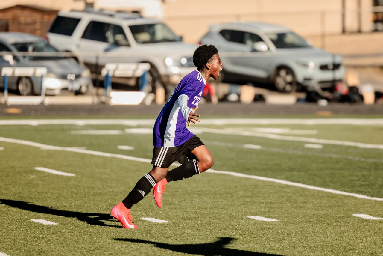 A male middle school soccer player runs across the field during a game.