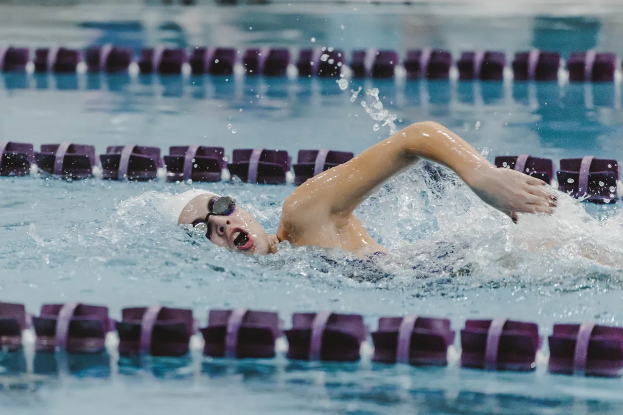 Female middle school swimmer swims through the pool during a swim meet.