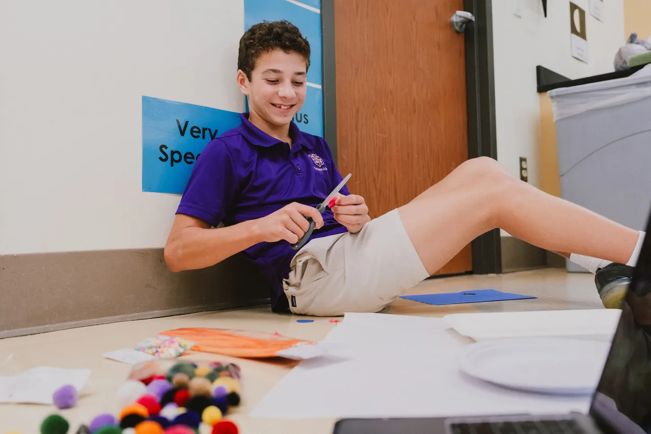 Male middle school student does an active learning activity in the hallway during science class