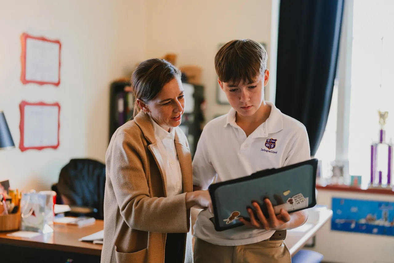Female teacher works with male middle school student on his MacBook