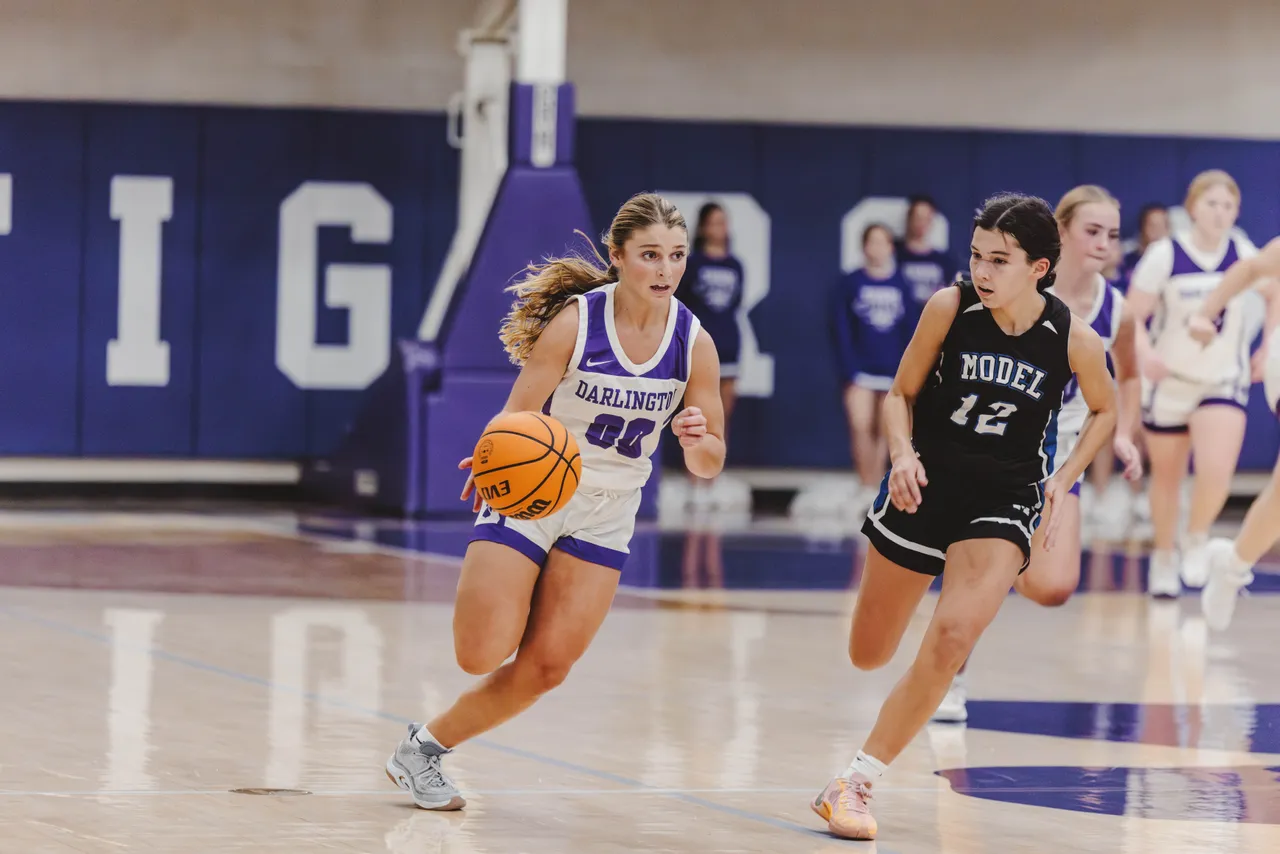 Female middle school basketball player runs down the court with the ball