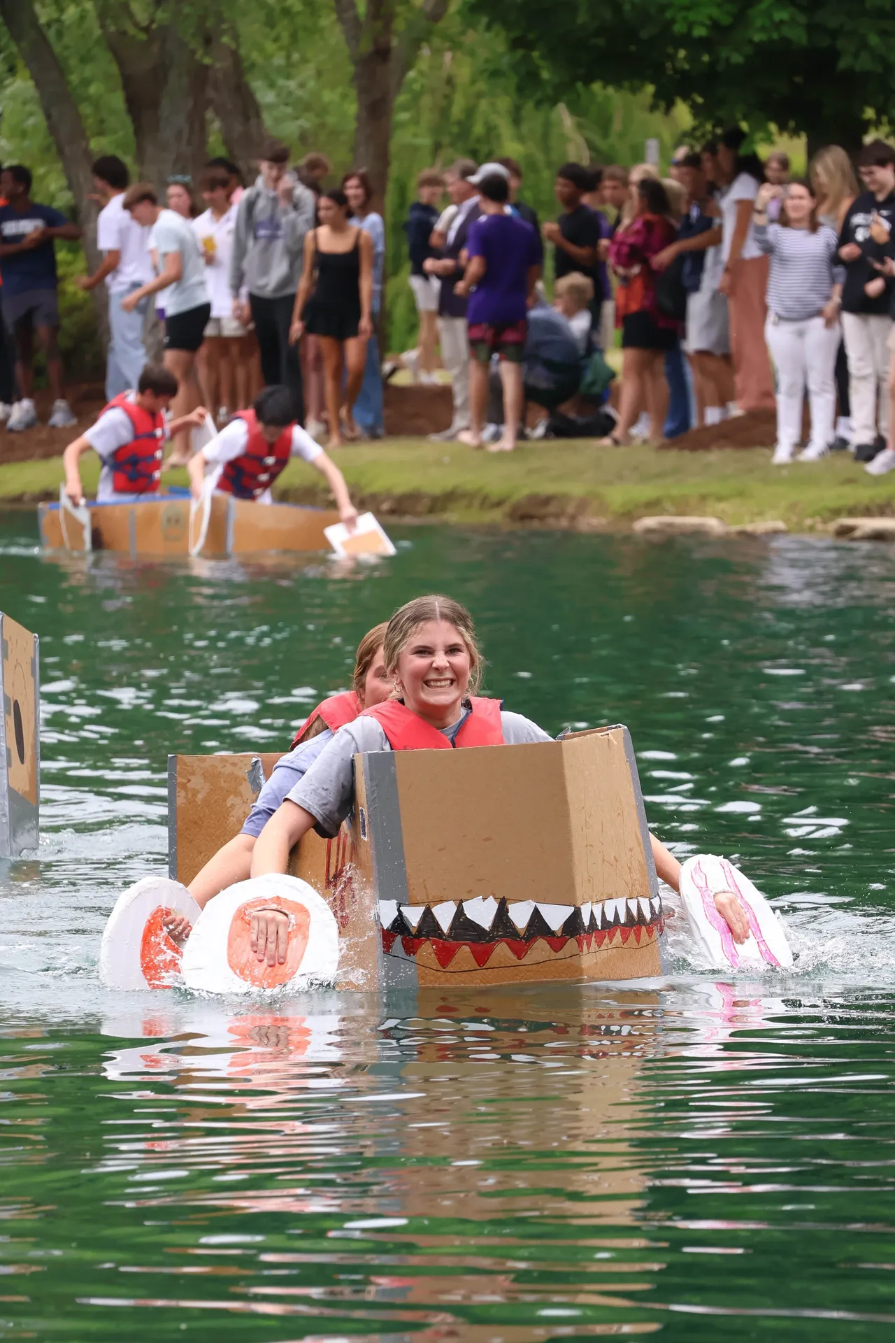 Female student paddles a handmade cardboard boat during Darlington School's annual physics boat race.