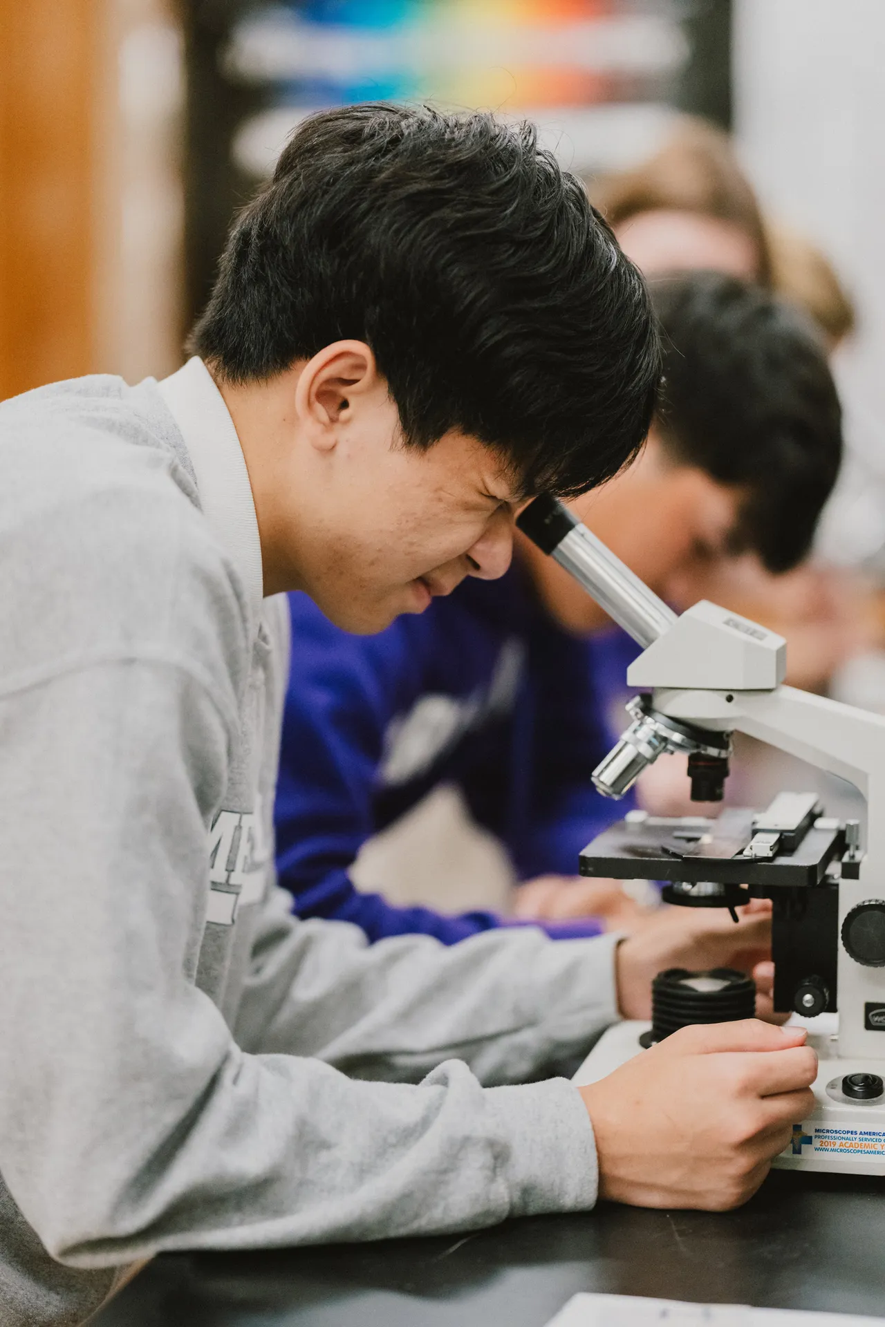 Male student looks through a microscope in the science lab