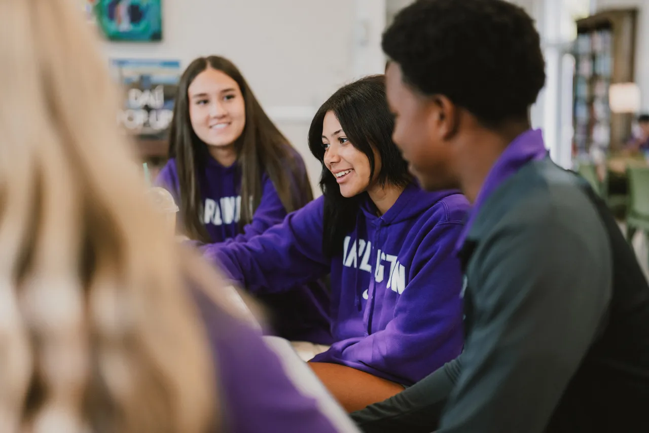 A group of students work together in a classrom while smiling