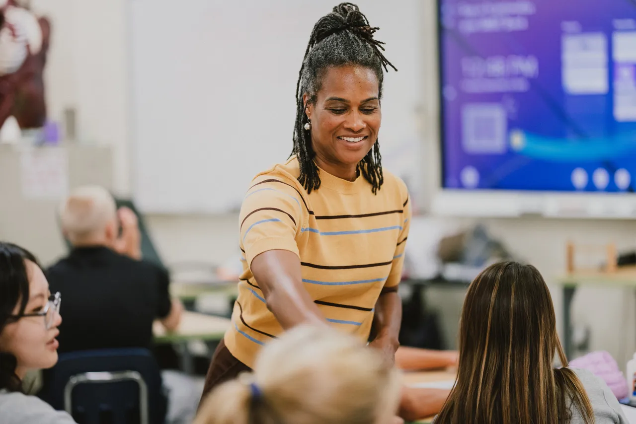 Female high school science teacher interacts with students during class