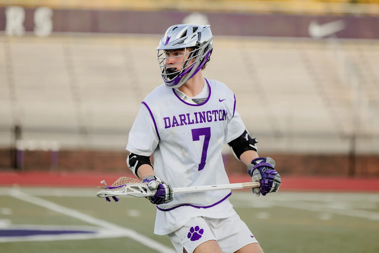 Male high school student plays lacrosse on the field