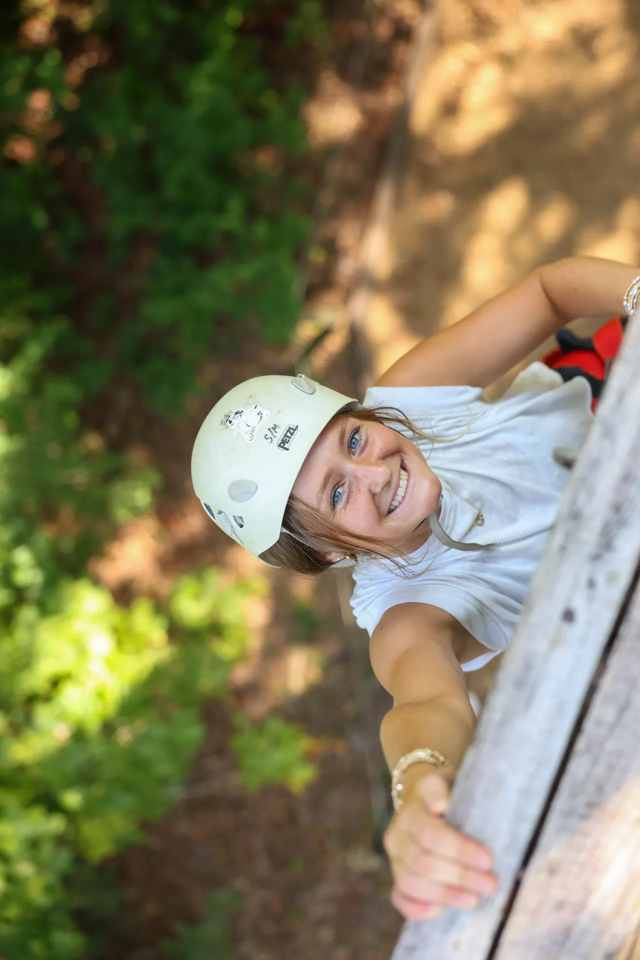 Female high school student climbs a rock wall at the senior retreat