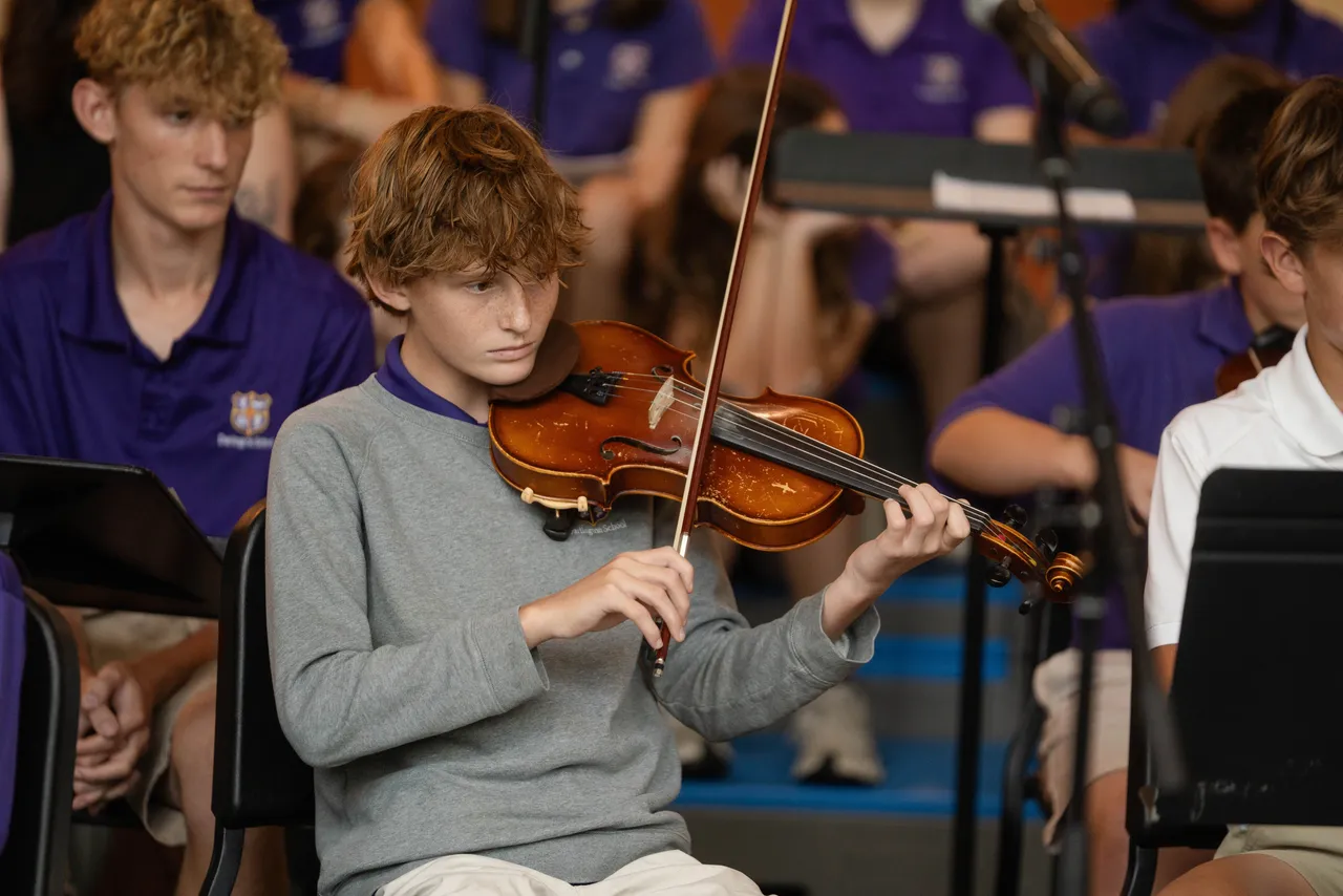 Male middle school student plays the violin at a concert