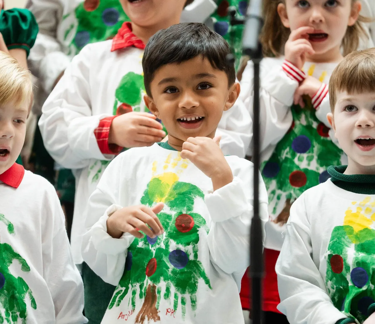 Primary grades students sing a song during a holiday recital while dressed in festive holiday clothing