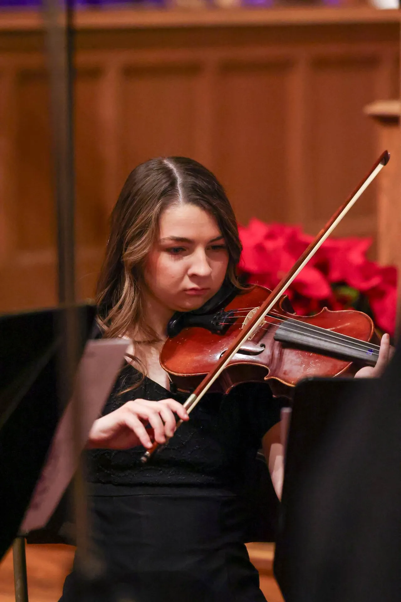 A female high school student plays a string instrument during a holiday concert