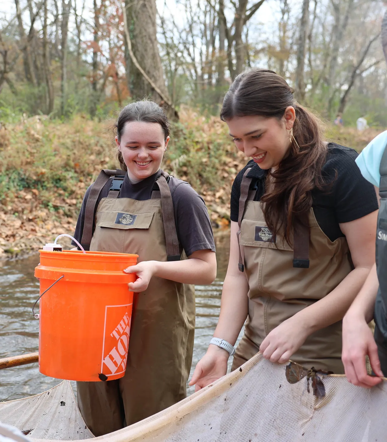 Two female students do a river cleanup activity with their Environmental Science class