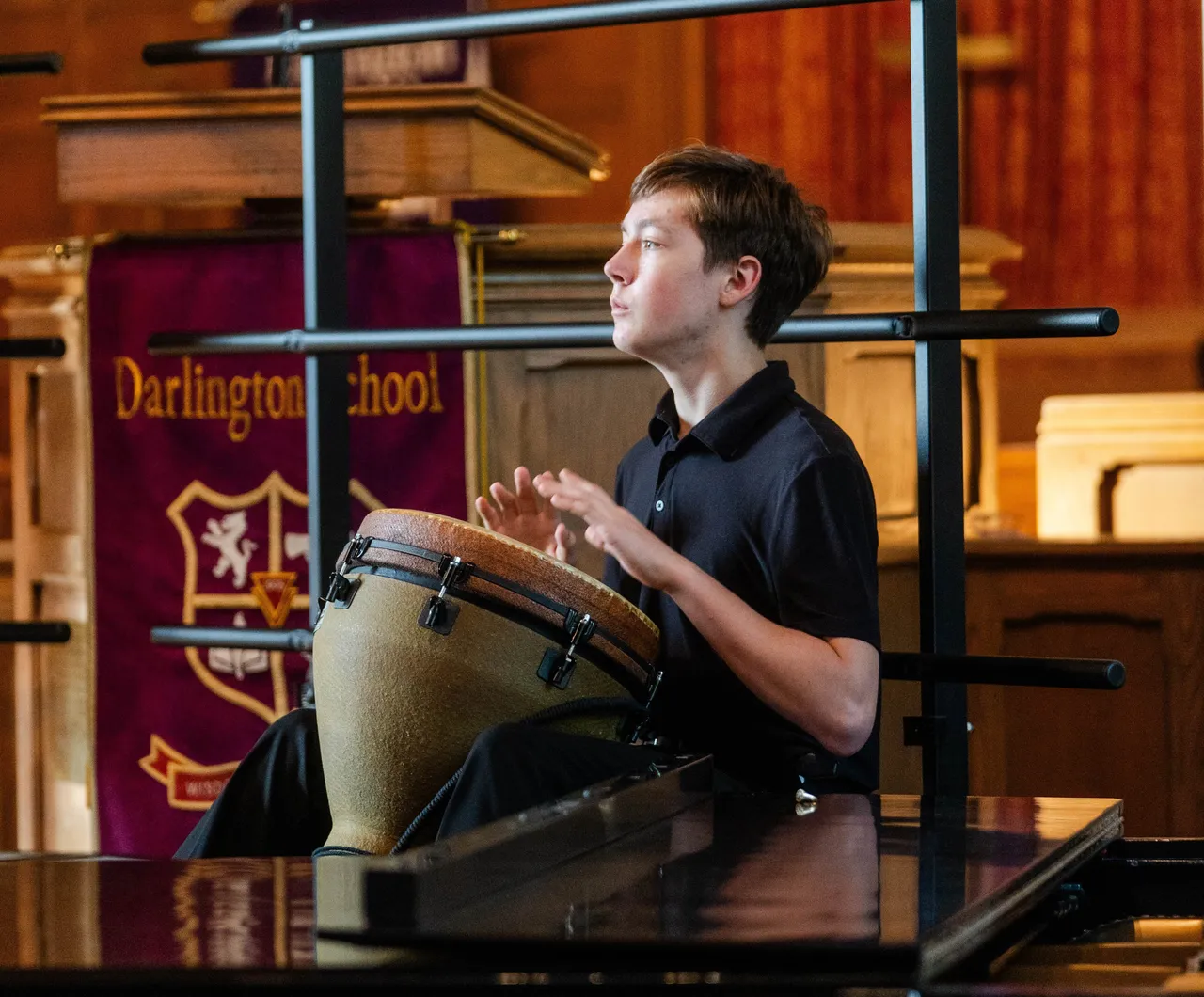 A male student plays a drum during a recital