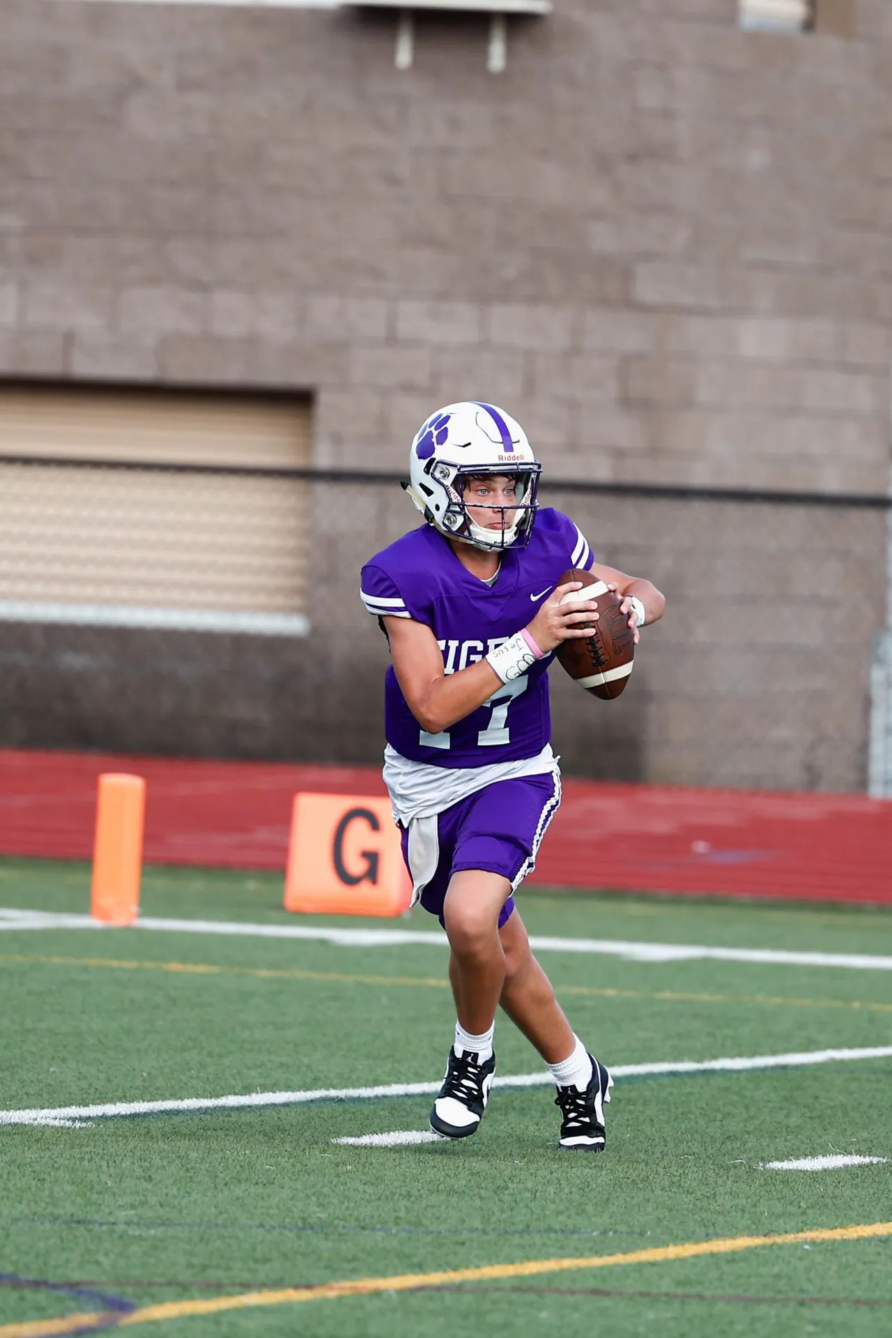 Male high school football player runs with the football during a game