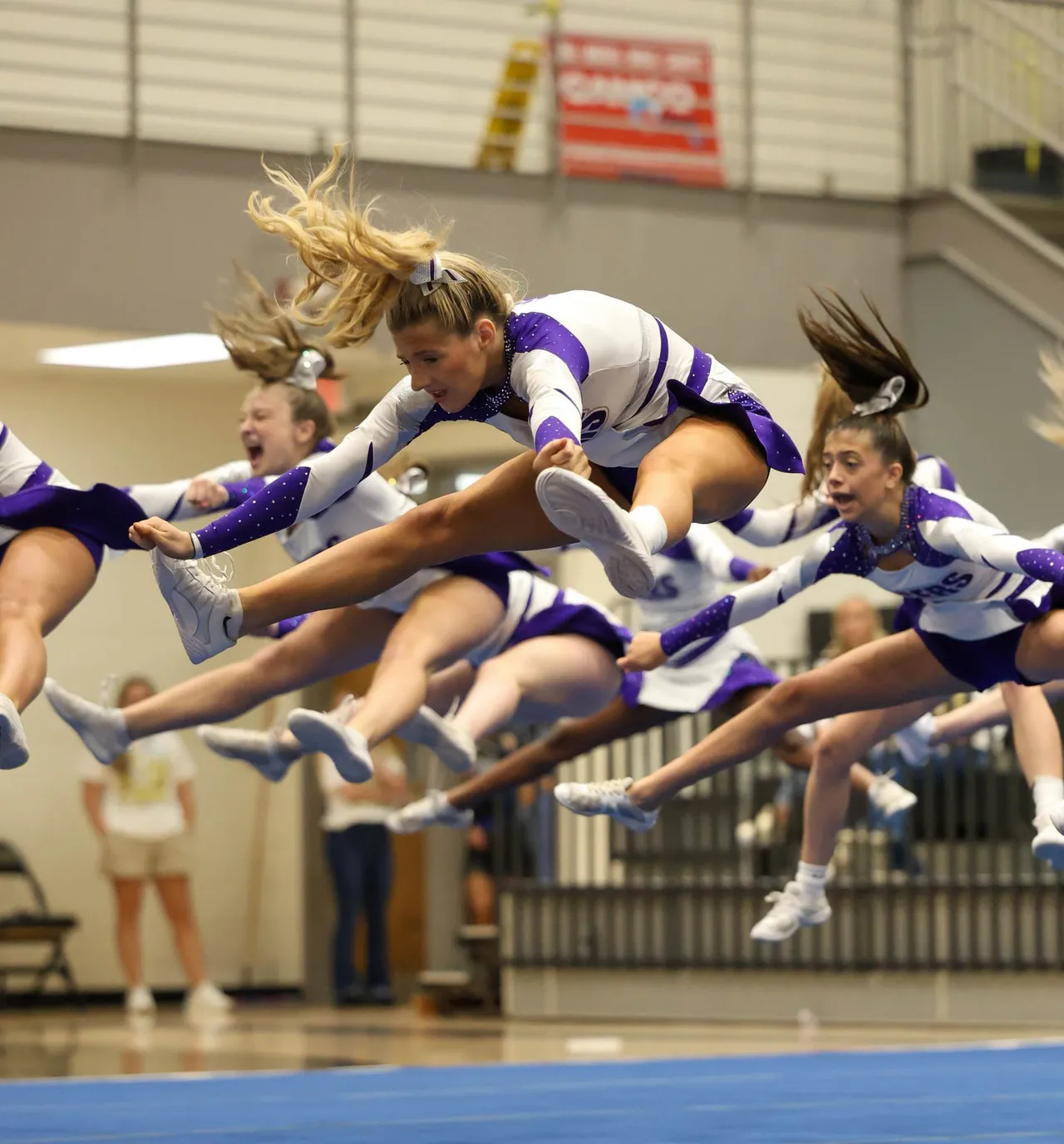 High school cheerleaders do a toe touch during their cheerleading routine in the gym