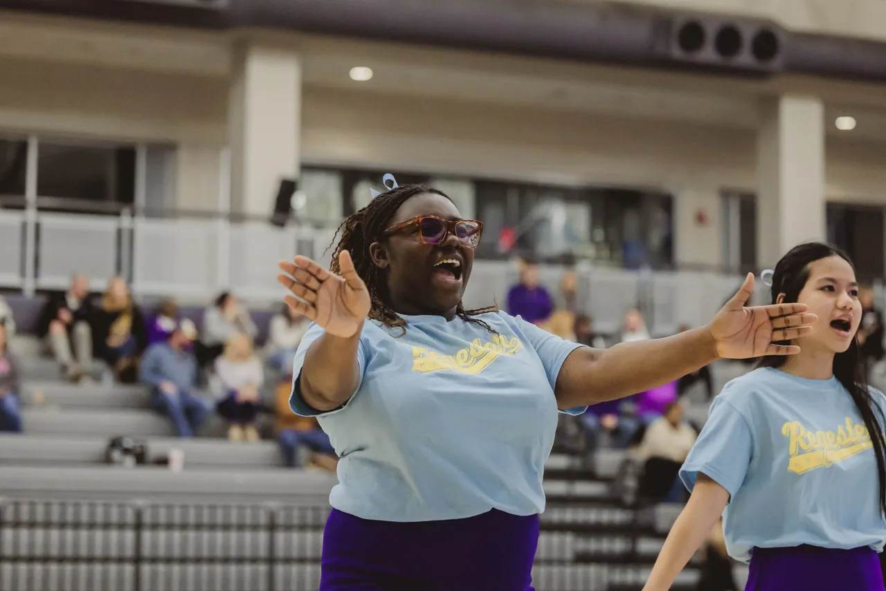 A cheerleader does a cheer during a high school basketball game