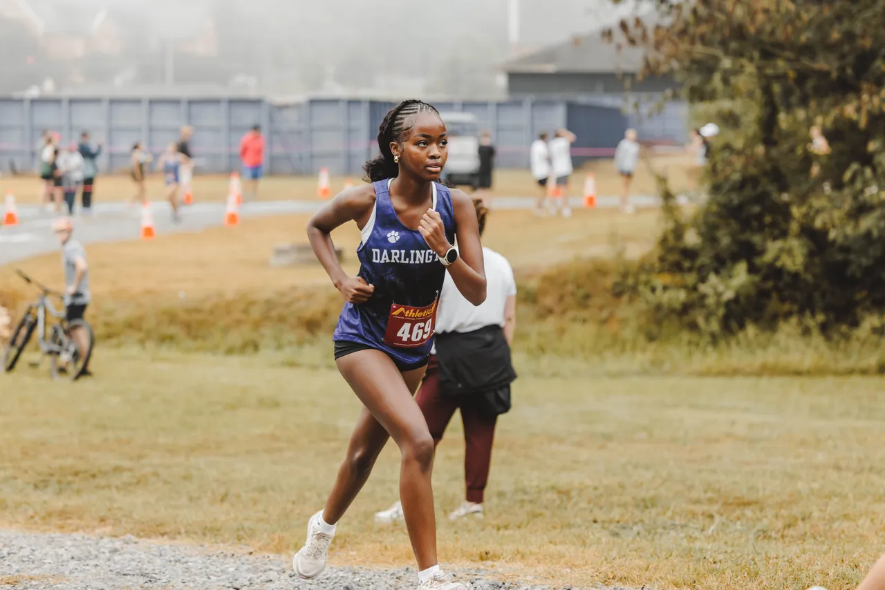 A female high school student runs on a cross country trail
