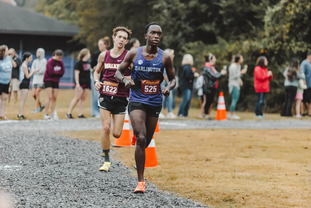 High school boy runs on the cross country course during a meet