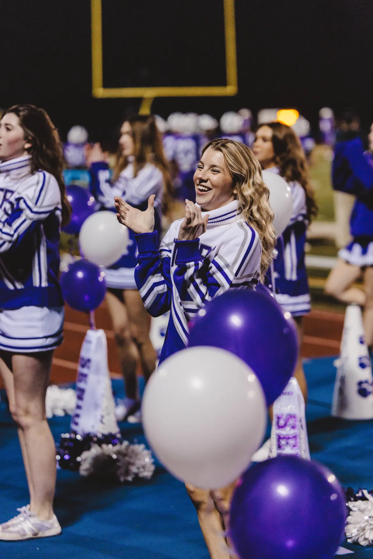 High school cheerleaders do a cheer on the sidelines during a football game