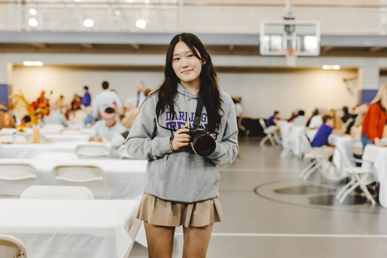 A female high school student takes photos at an event in the athletic center