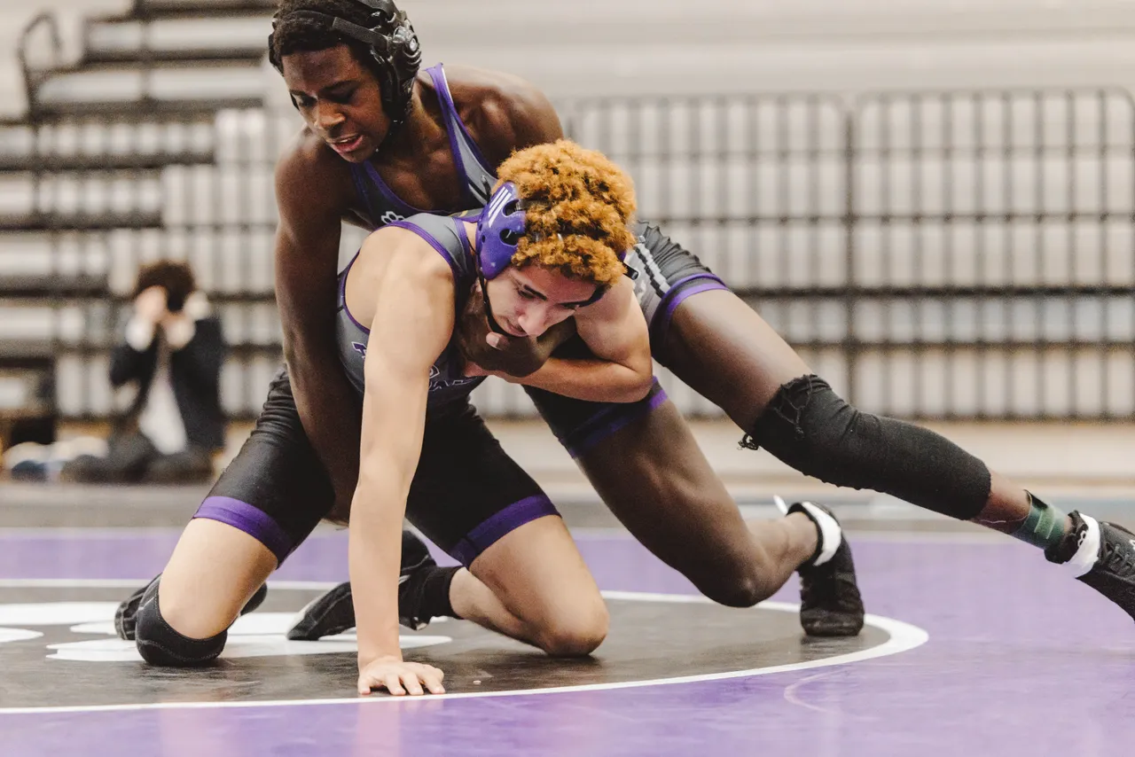 Two male high school wrestlers wrestle on the mat during a match