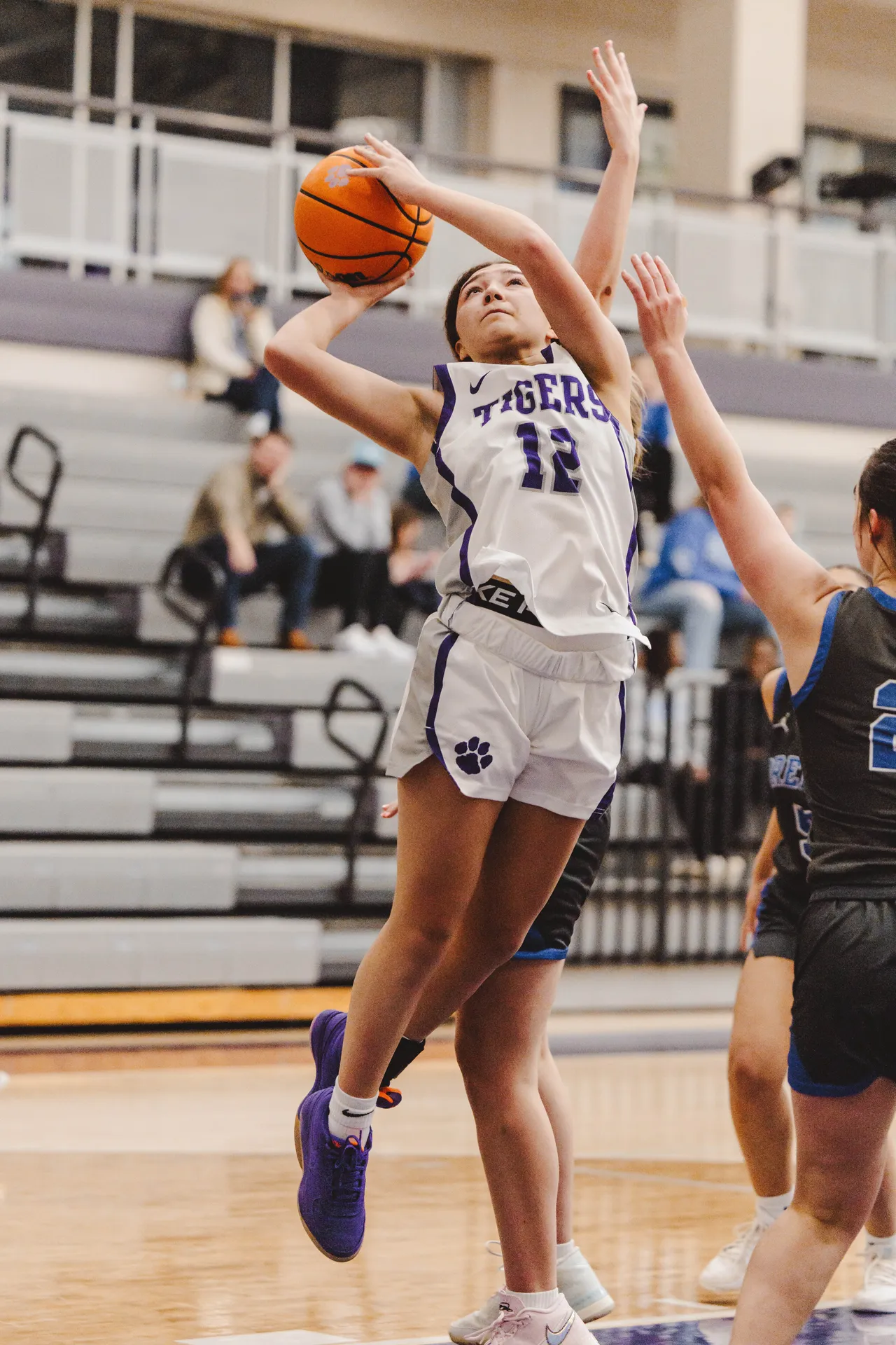A female high school basketball player shoots the ball toward the basket