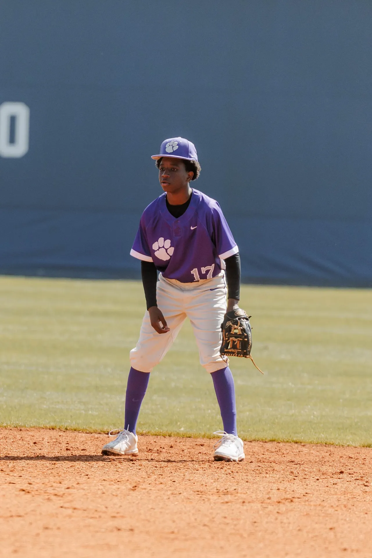 Male high school baseball player stands ready with his glove on his left hand during a baseball game