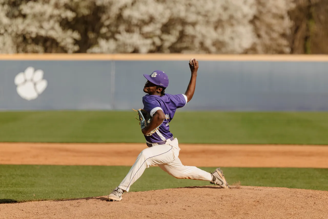 A male high school baseball player throws the ball on the baseball field