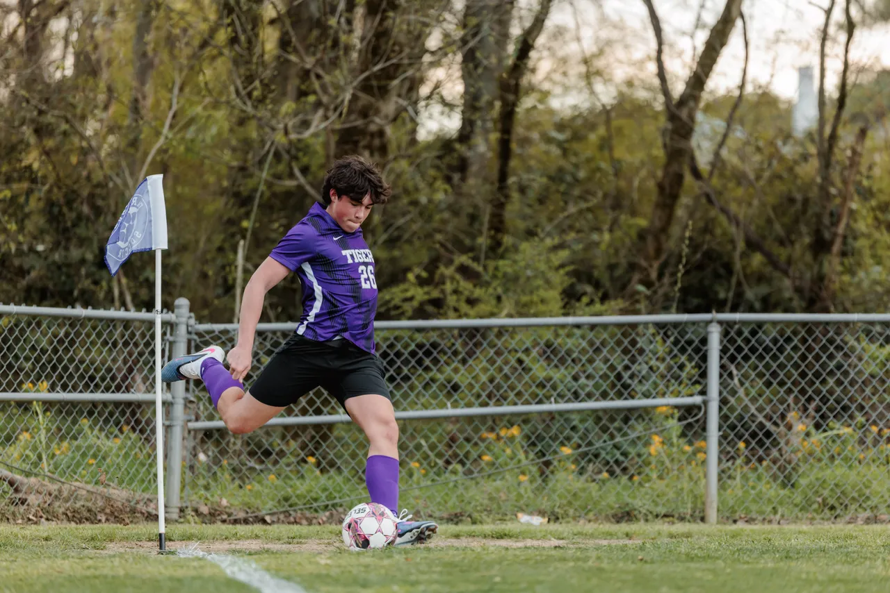 Male high school student kicks the soccer ball from the corner of the field
