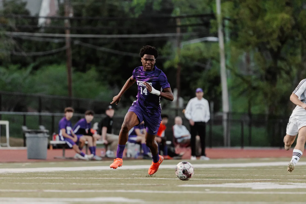 Male high school soccer player runs toward the ball on the soccer field
