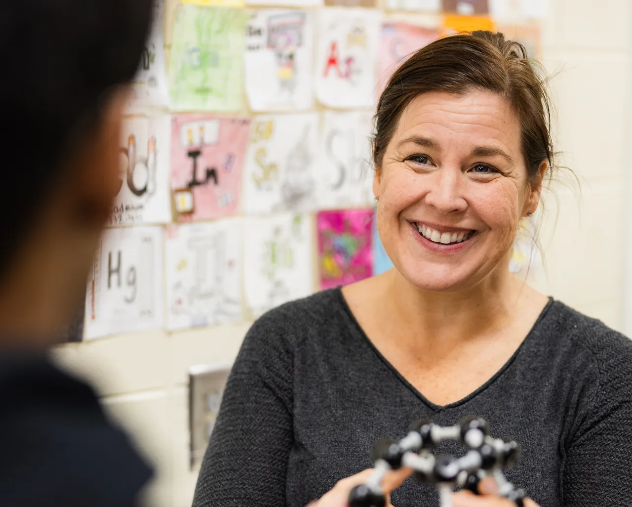 Female high school science teacher works with a student in class