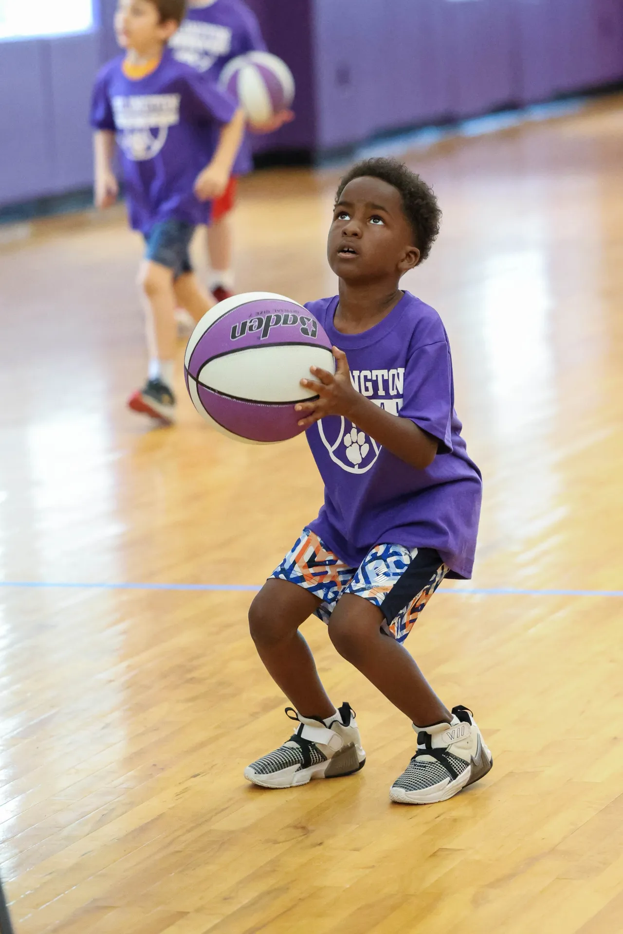Young male camper prepares to shoot a basketball during Youth Boys' Basketball Camp.