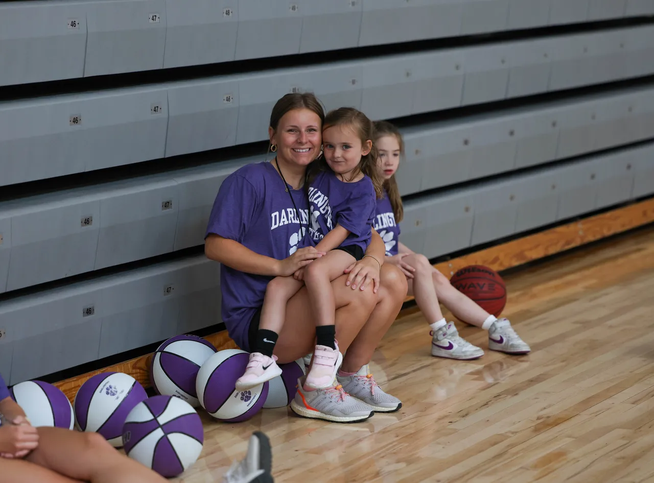 Female counselor sits with a young female camper during Lady Tiger Basketball Camp.