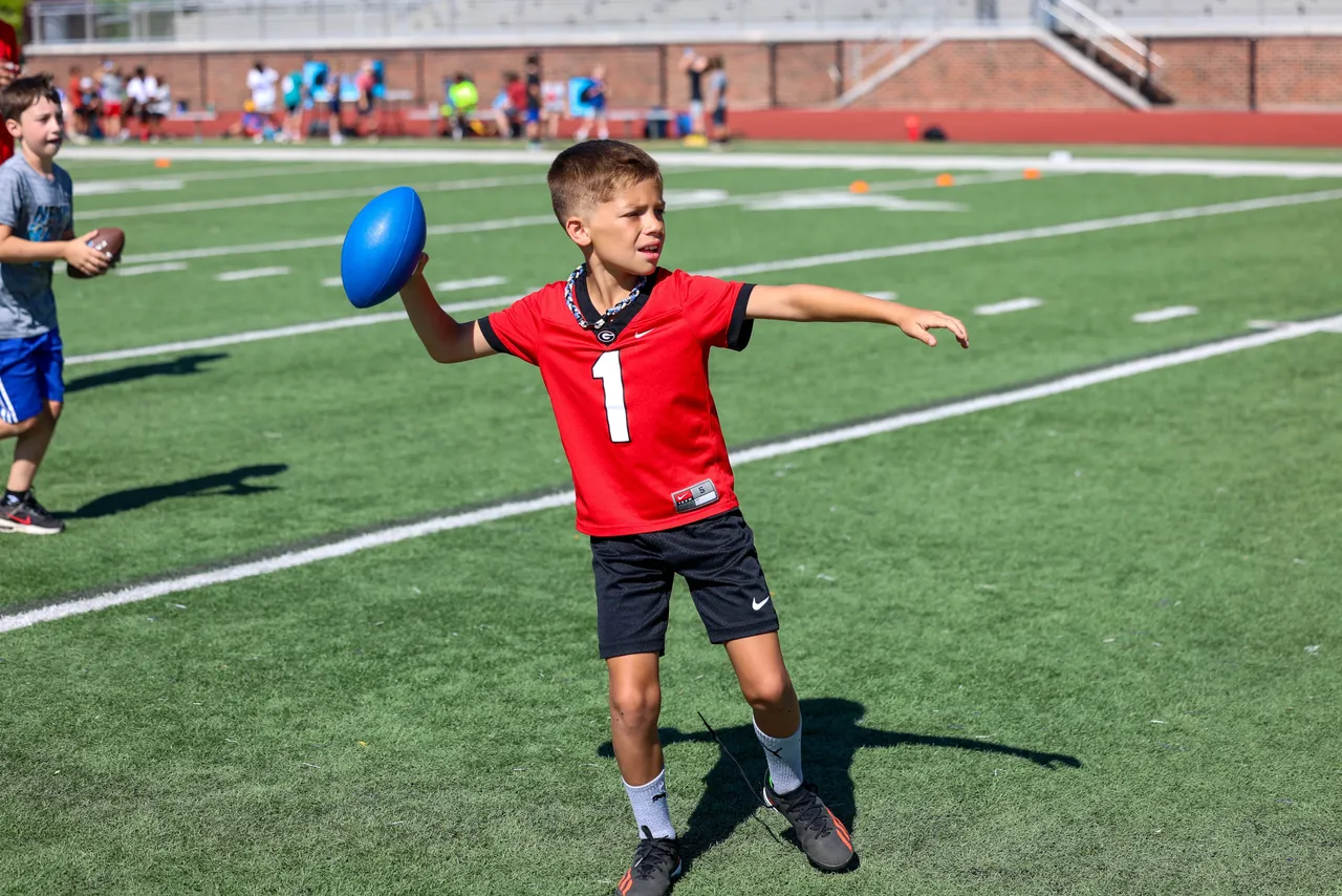 Young male camper throws a football during Youth Football Camp.