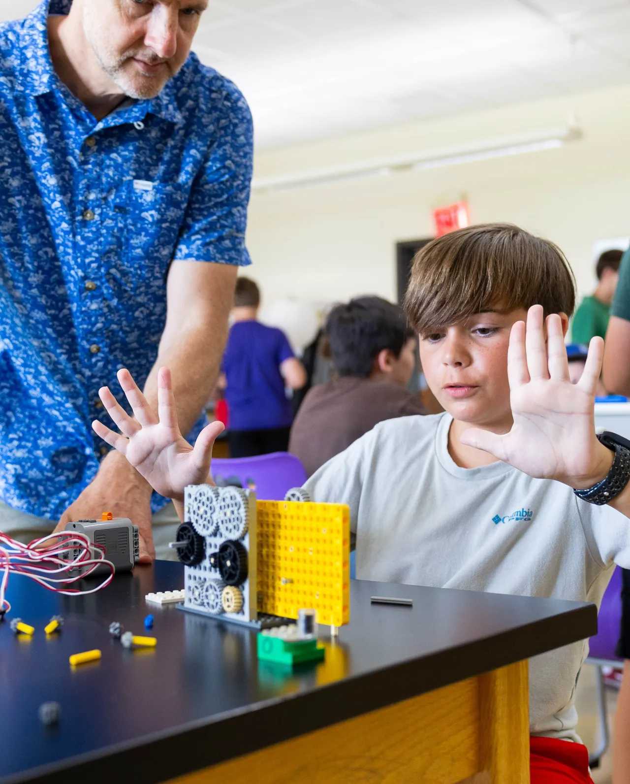 Male faculty member works with a young male camper during Maker Challenge Camp.