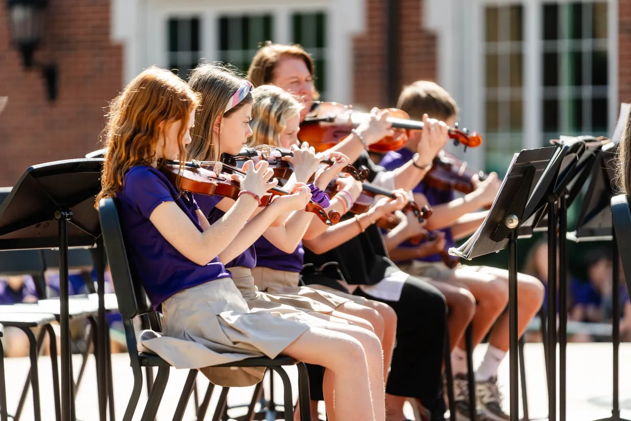 Five students play their string instruments during an outdoor concert on the Darlington School campus