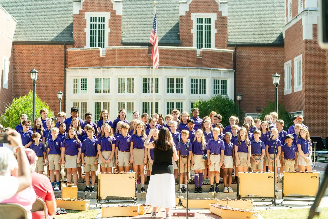 A large group of lower grades students sing during an outdoor concert