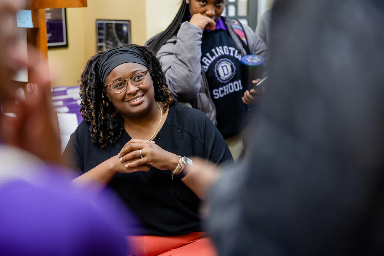 A female faculty member talks with students in her office during break as they gather around her desk