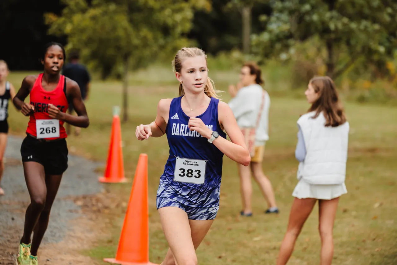 A female high school student runs on a cross country trail