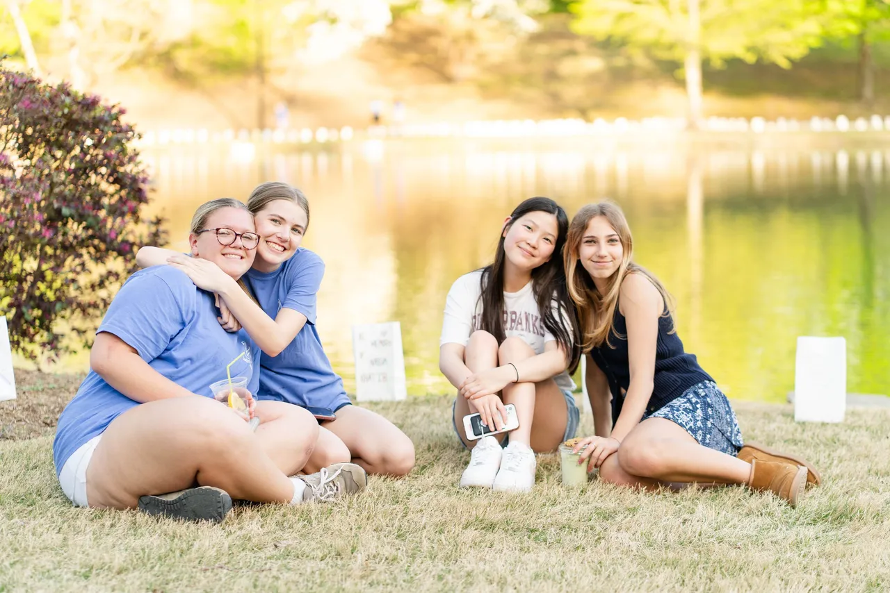 Four female high school students sit together by Silver Lake on the Darlington School campus