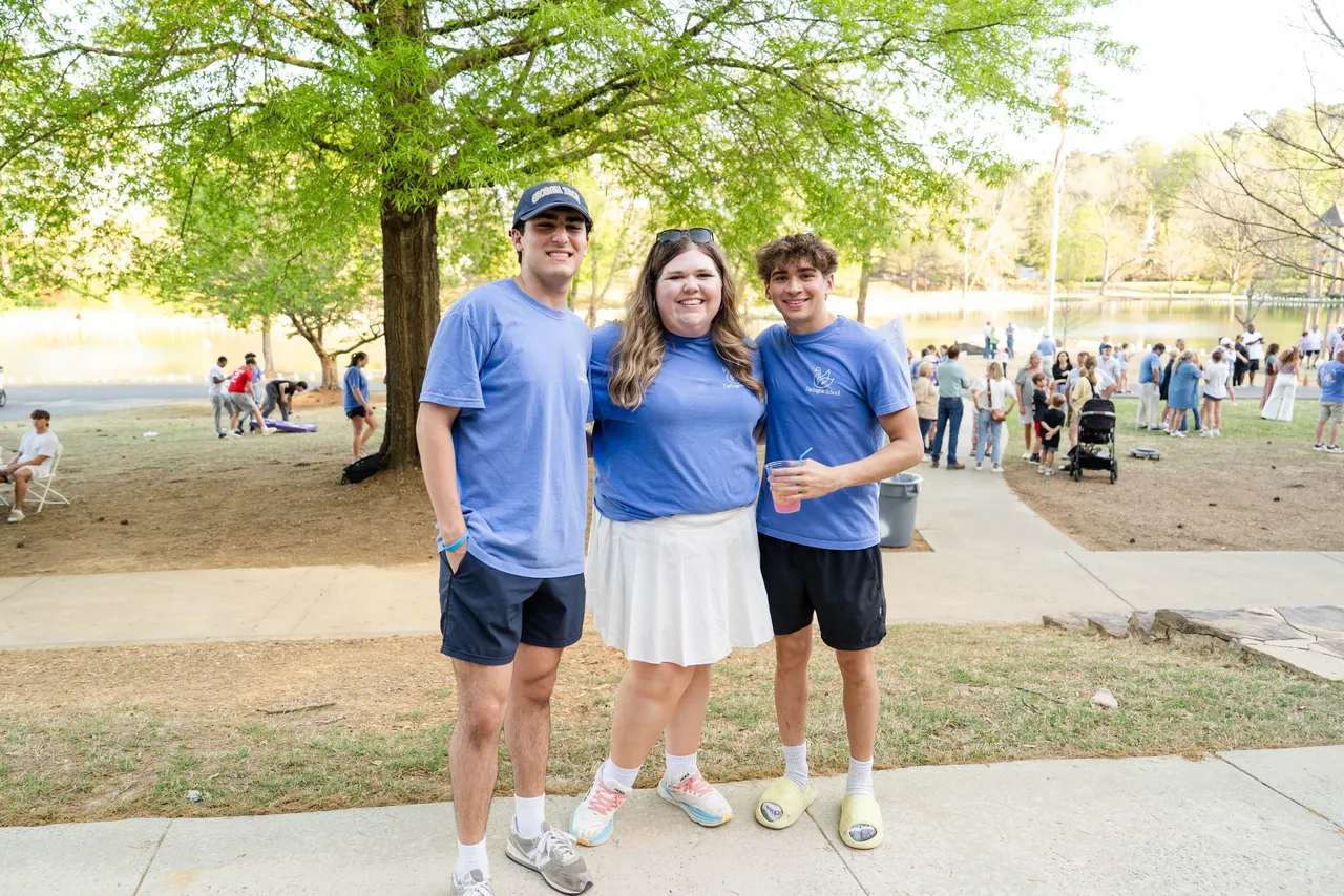 A female faculty member hugs two male high school students during the Light the Lake fundraiser event