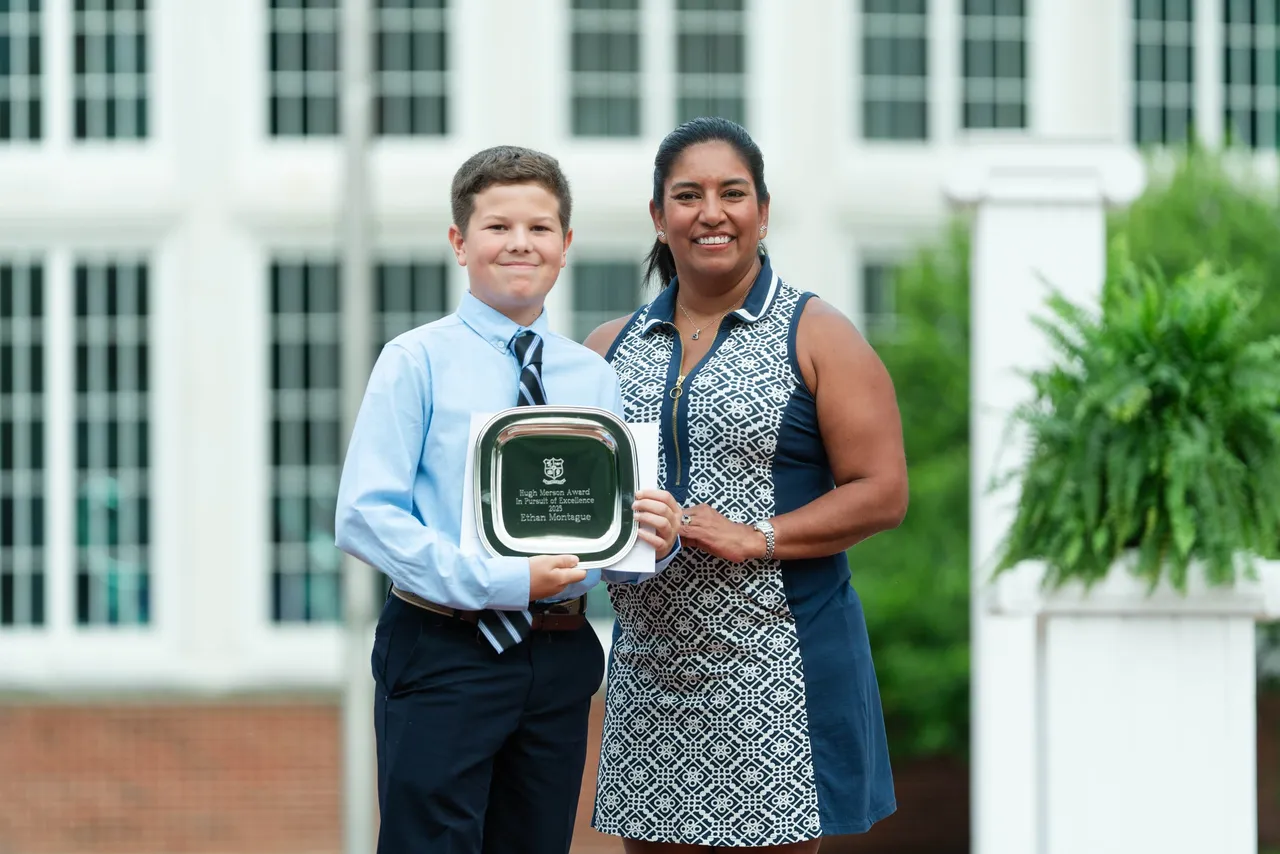 A female middle school teacher presents an award to a male student at the 8th Grade Moving Up Ceremony at Darlington School