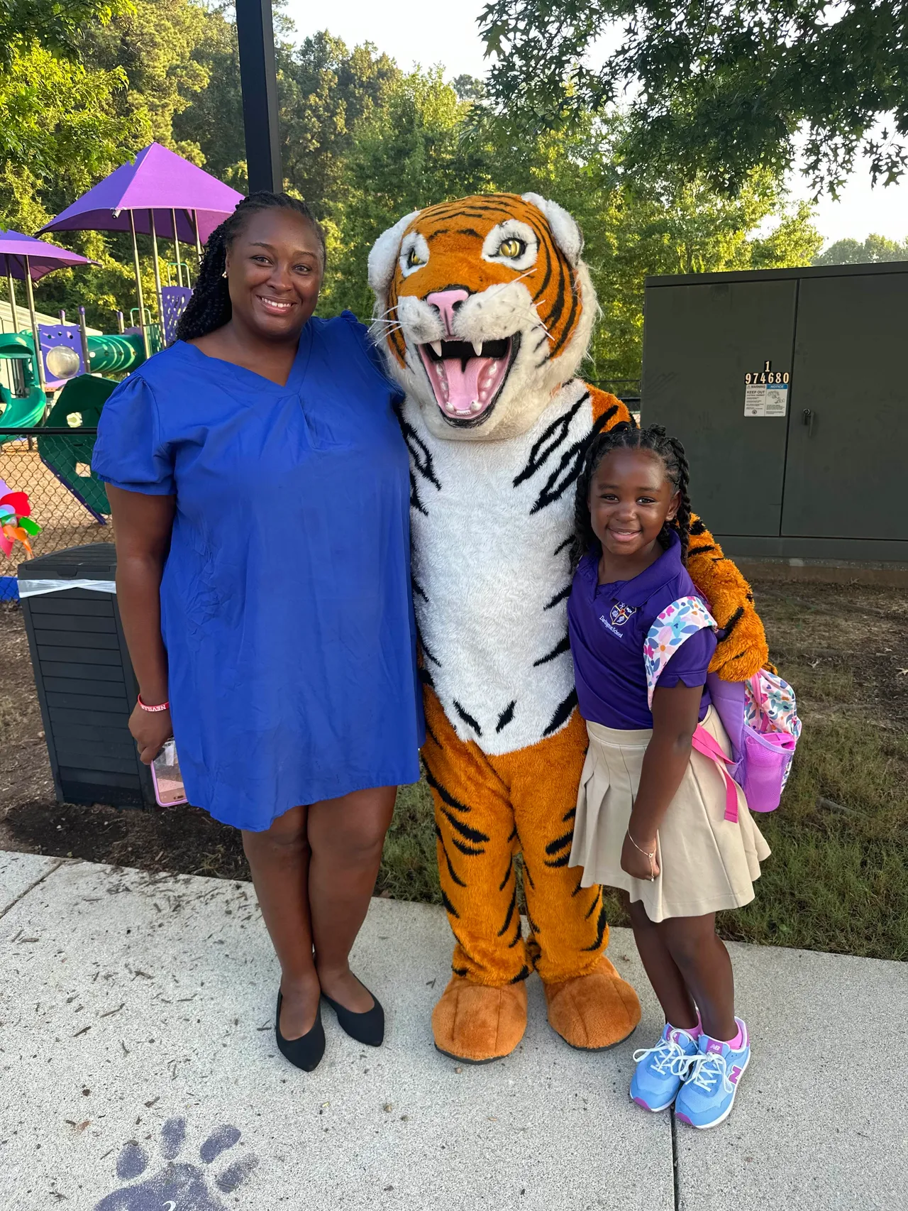 Female faculty member poses with her daughter and the Darlington School tiger mascot.